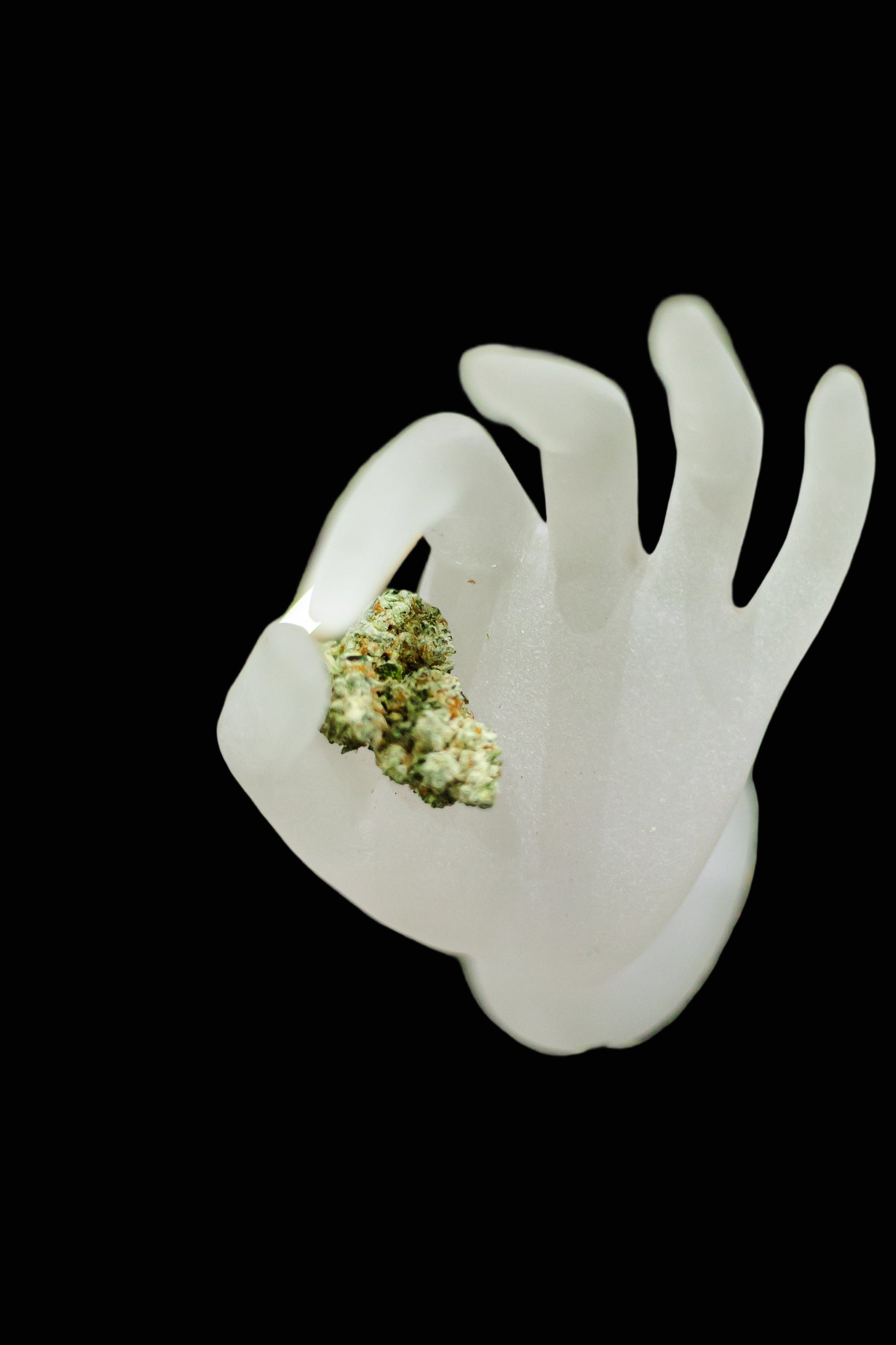 White hand-shaped object with green substance on a grassy background