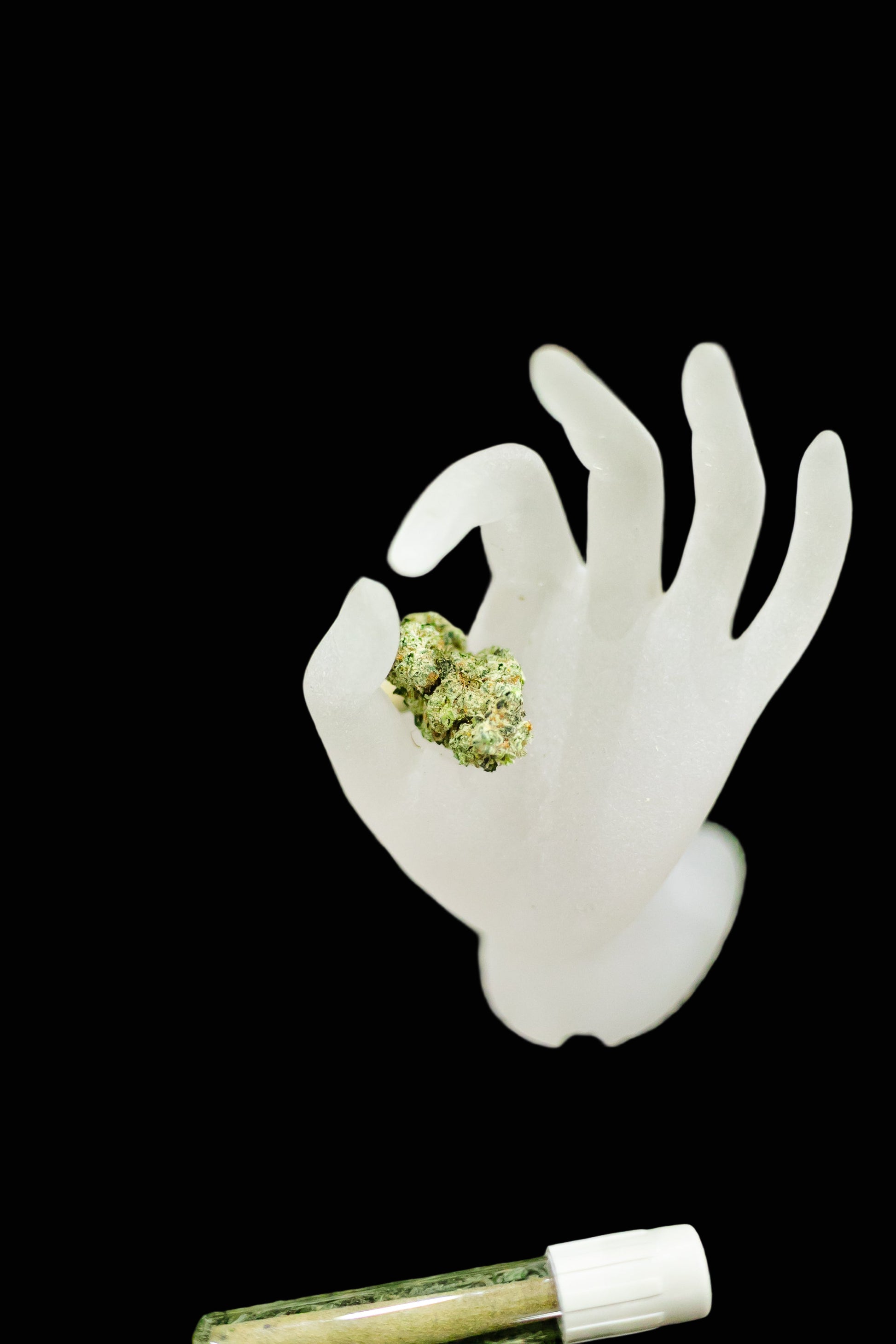 White silicone hand mold with cannabis buds on a green grass background