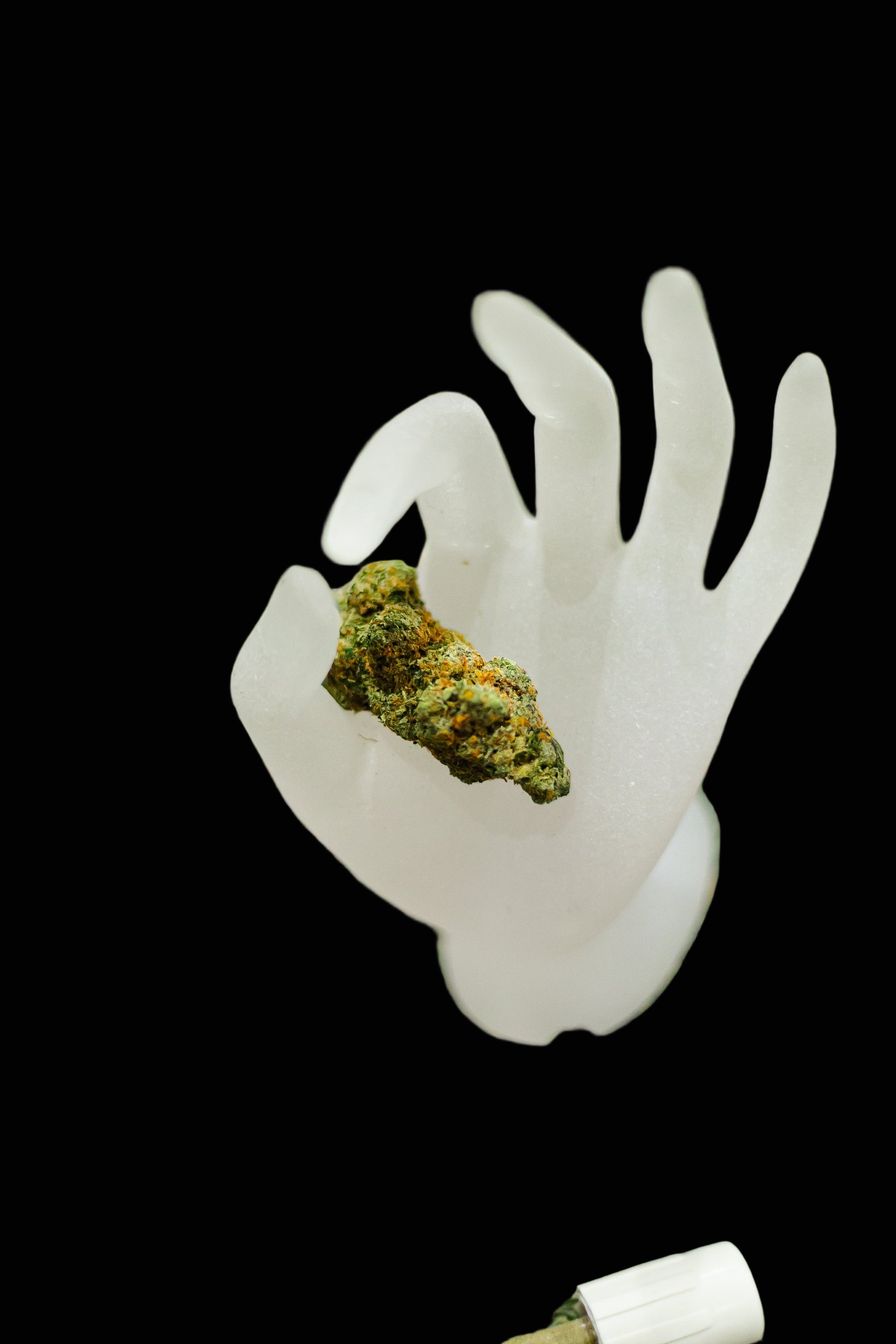 White hand-shaped object with a clump of green substance on a grassy background